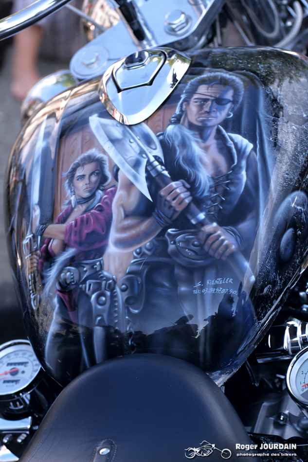 Gros plan sur l'aérographe d'un guerrier barbare avec une hache, peint sur le réservoir d'une moto au Free Wheels.