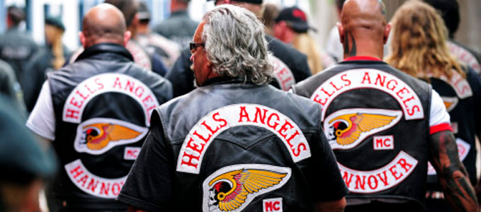 Des membres du club de motards Hells Angels vus de dos, portant leurs vestes en cuir avec les logos "Hells Angels MC" et le nom du chapitre "HANNOVER" sur un des blousons.