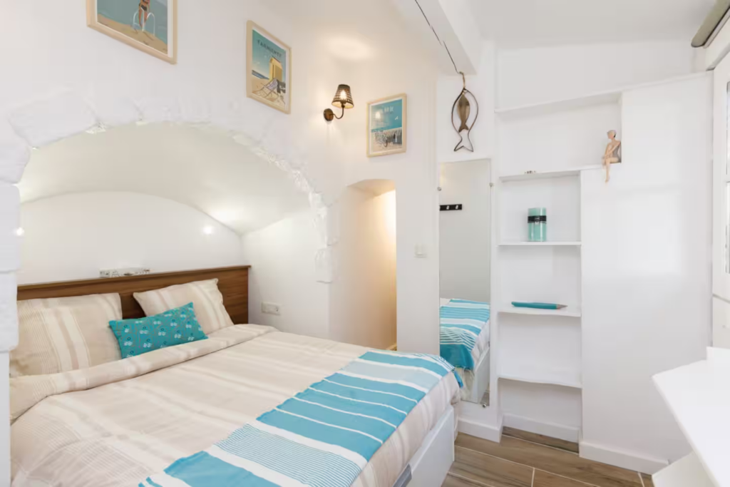 Chambre lumineuse avec lit double, rangements intégrés et décoration méditerranéenne dans un studio tout équipé