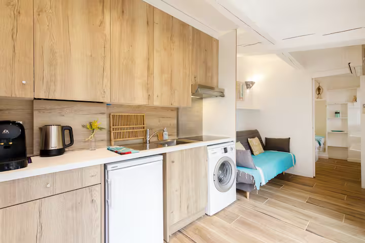 Kitchenette équipée avec lave-linge, réfrigérateur et espace de vie dans un studio moderne et fonctionnel