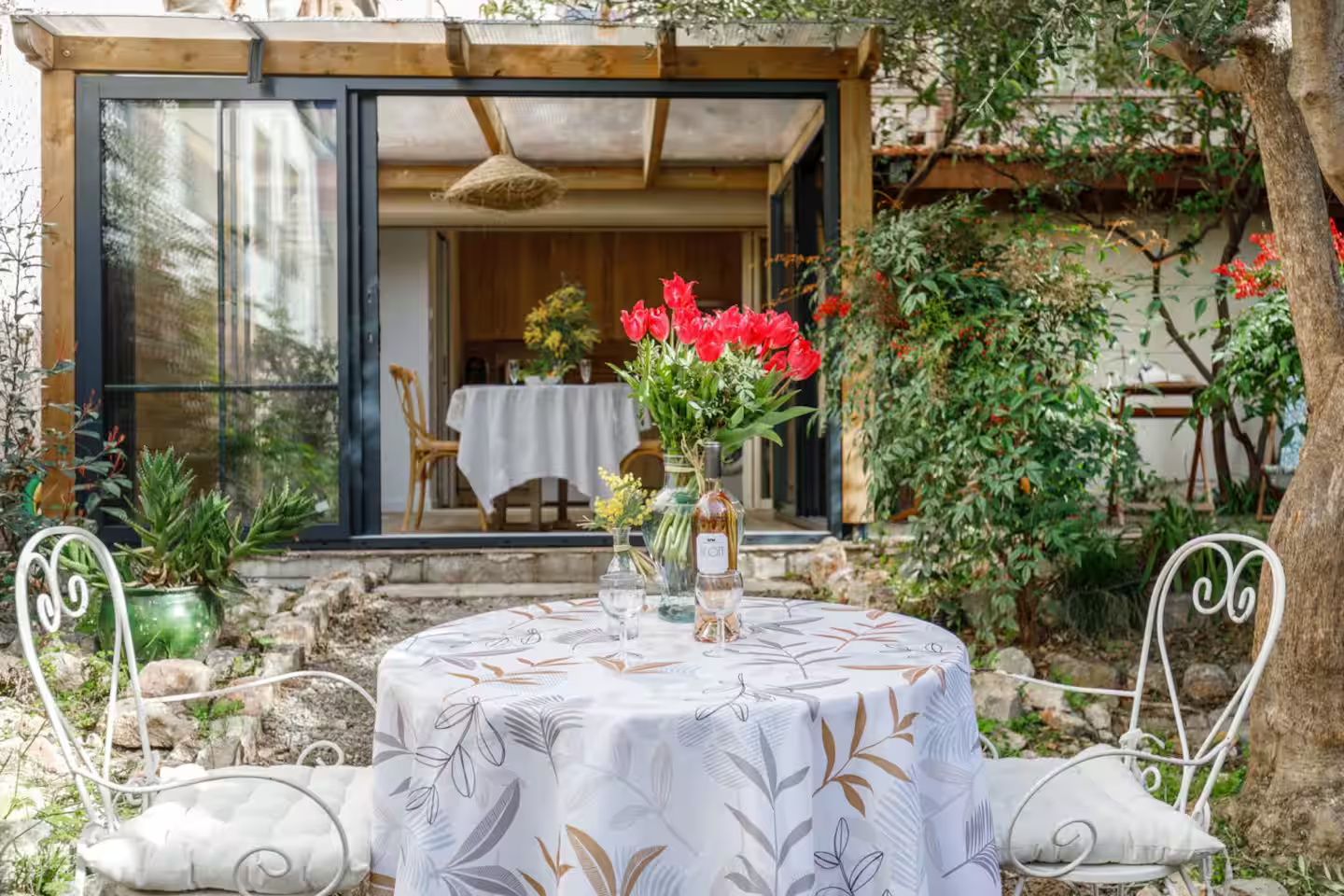Terrasse fleurie avec table dressée dans un jardin provençal romantique et chaleureux