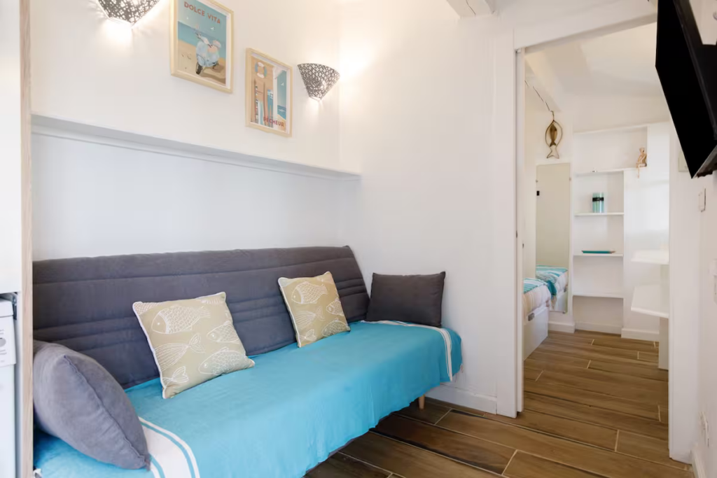 Pièce de vie lumineuse avec canapé convertible et espace nuit dans un appartement à Cannes