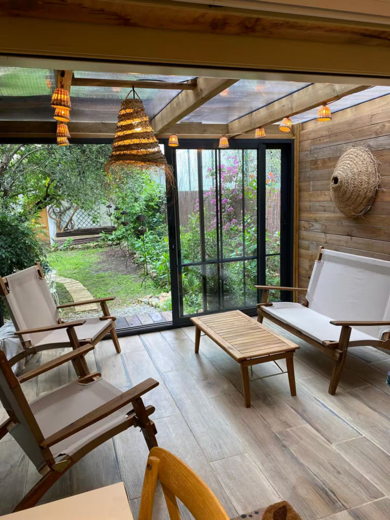 Véranda lumineuse avec fauteuils en bois et vue sur un jardin privatif dans une propriété à Cannes